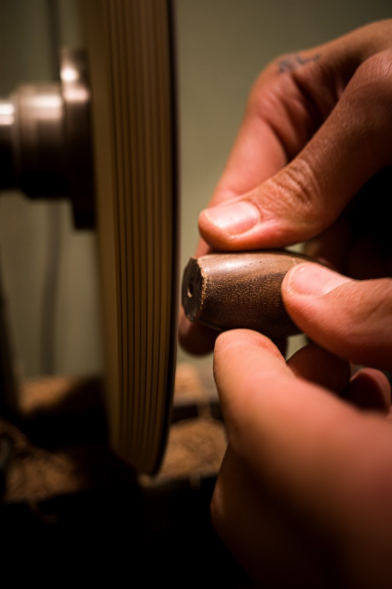 Hands shaping a wooden piece by hand at the workbench